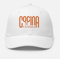 White trucker cap with 'Cocina Casera' logo mark in orange